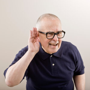 Man cupping his ear having difficulty hearing