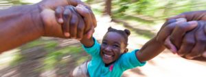 Young girl being spun in a circle holding her father's hands